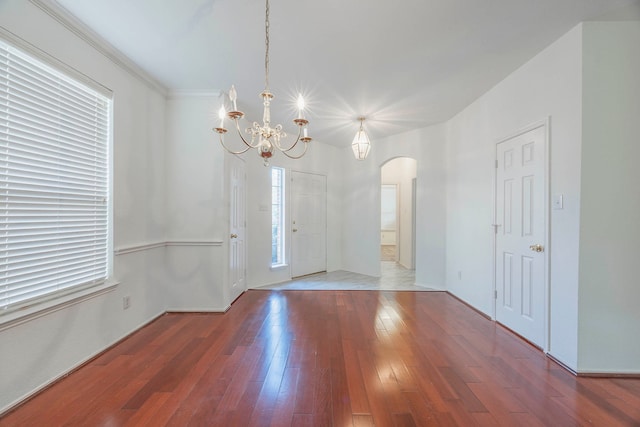 spare room with a chandelier, hardwood / wood-style floors, and crown molding