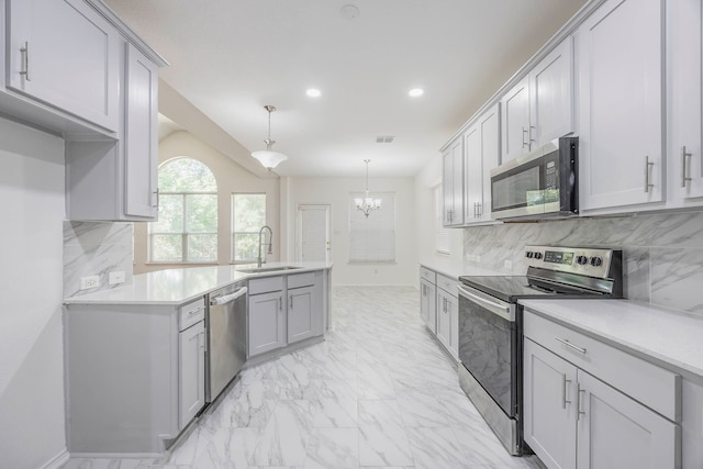 kitchen with appliances with stainless steel finishes, hanging light fixtures, decorative backsplash, gray cabinets, and sink