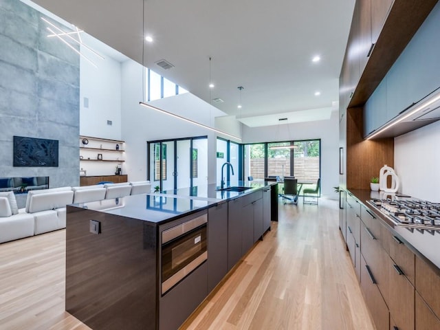 kitchen featuring light wood-type flooring, hanging light fixtures, a large island, and sink