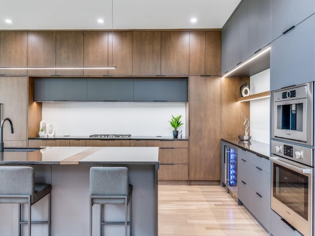 kitchen featuring stainless steel appliances, light hardwood / wood-style floors, a breakfast bar area, and sink