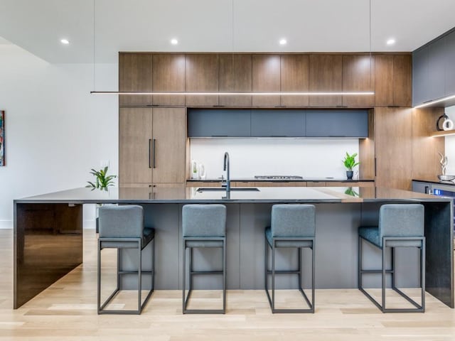 kitchen featuring light hardwood / wood-style floors, sink, a breakfast bar area, and an island with sink