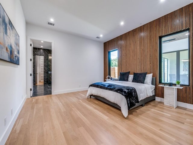 bedroom featuring light wood-type flooring and wooden walls