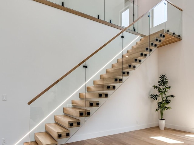 staircase featuring hardwood / wood-style floors and a towering ceiling