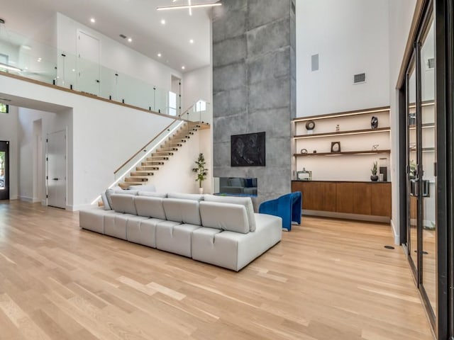 living room featuring a tile fireplace, a high ceiling, and light hardwood / wood-style flooring