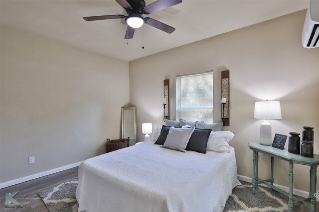 bedroom with dark hardwood / wood-style flooring, a wall mounted AC, and ceiling fan