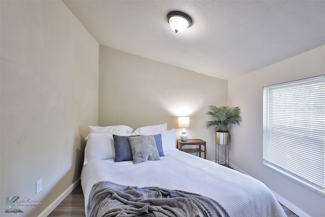 bedroom featuring lofted ceiling, dark wood-type flooring, and a textured ceiling