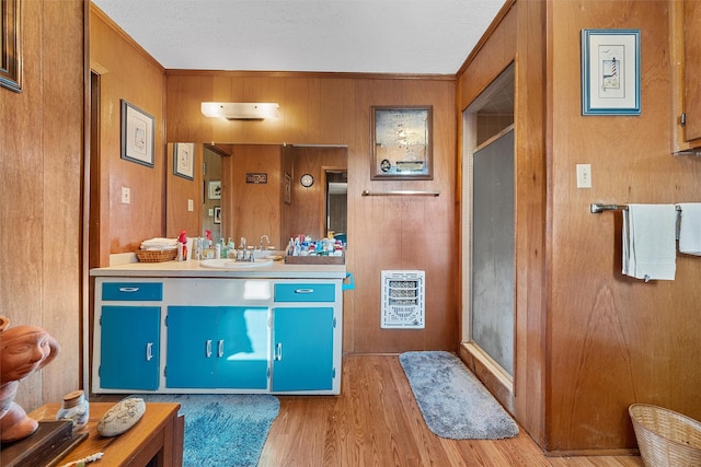 bathroom featuring heating unit, vanity, and wooden walls