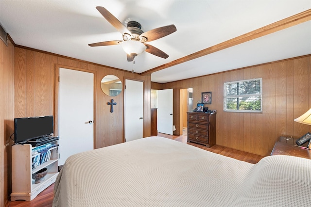 bedroom with ceiling fan, wood-type flooring, crown molding, and wooden walls