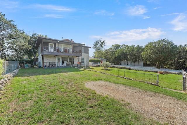 rear view of property with a balcony and a lawn