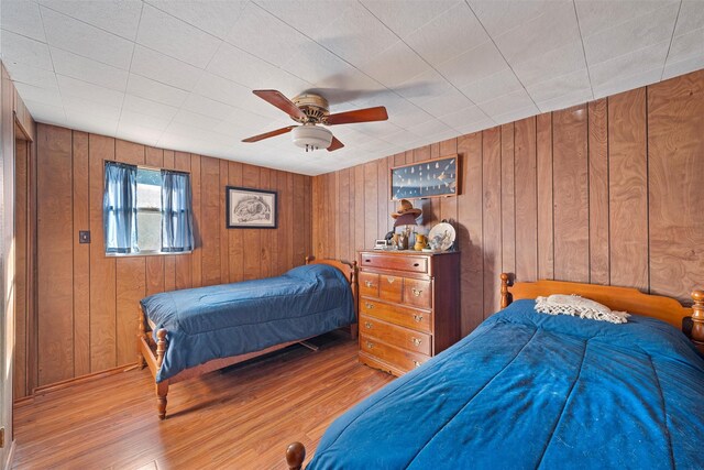 bedroom featuring wood walls, ceiling fan, and light hardwood / wood-style flooring