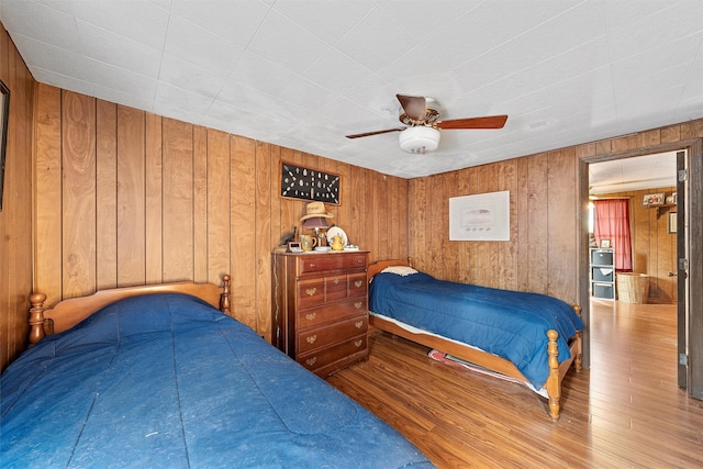 bedroom featuring ceiling fan, hardwood / wood-style floors, and wood walls