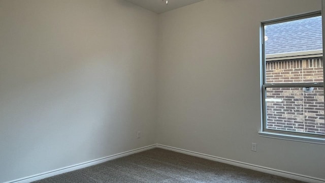 spare room featuring baseboards and dark colored carpet