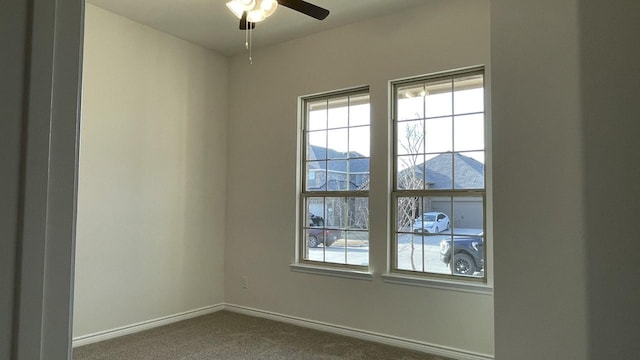 unfurnished room featuring ceiling fan, dark carpet, and baseboards