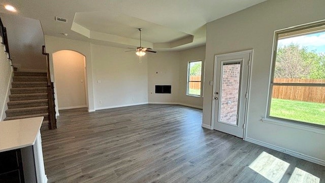 unfurnished living room featuring ceiling fan, a tray ceiling, and wood-type flooring