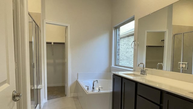 bathroom featuring a spacious closet, a stall shower, a sink, tile patterned flooring, and a bath