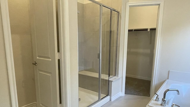 full bath featuring a stall shower, a garden tub, and a spacious closet