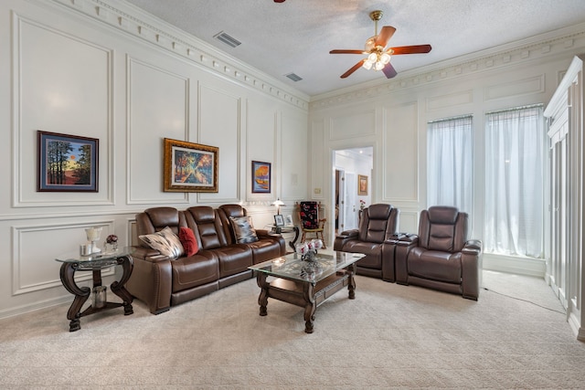 living room with a textured ceiling, ceiling fan, light colored carpet, and crown molding