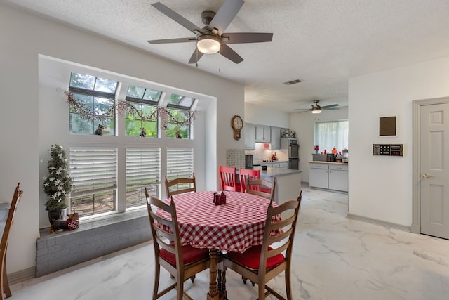dining space featuring visible vents, marble finish floor, a textured ceiling, baseboards, and ceiling fan