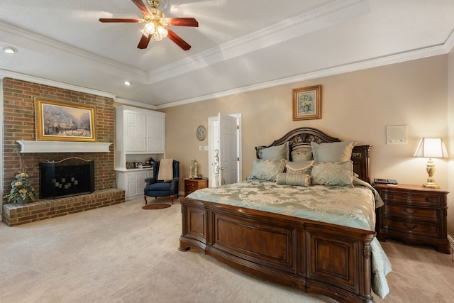 carpeted bedroom featuring a brick fireplace, ceiling fan, ornamental molding, and a tray ceiling