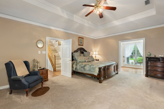 bedroom with visible vents, light colored carpet, a tray ceiling, and ornamental molding