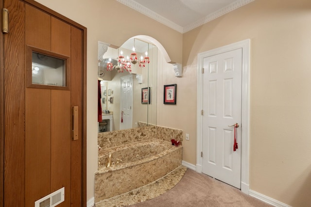 bathroom with a bath, an inviting chandelier, and ornamental molding