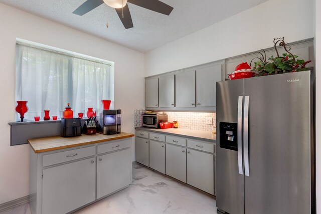 kitchen with backsplash, ceiling fan, gray cabinets, a textured ceiling, and stainless steel appliances