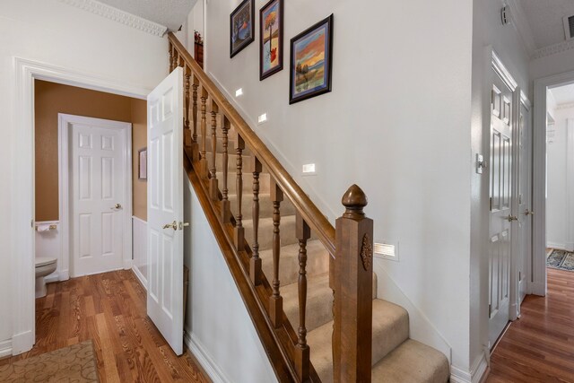 staircase with crown molding and wood-type flooring