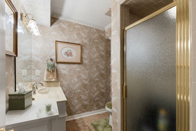 full bath featuring a shower stall, wallpapered walls, baseboards, vanity, and a textured ceiling