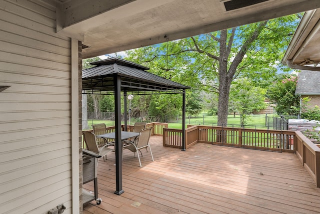 deck with a gazebo, a yard, outdoor dining space, and fence