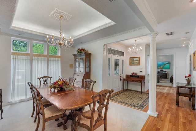 dining room featuring decorative columns, a tray ceiling, a textured ceiling, and an inviting chandelier