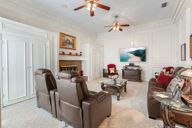 living room featuring a fireplace, ceiling fan, ornamental molding, and light carpet