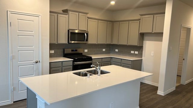 kitchen with gray cabinetry, a kitchen island with sink, dark hardwood / wood-style flooring, and stainless steel appliances