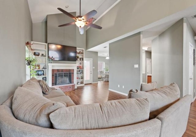 living room featuring ceiling fan, a fireplace, high vaulted ceiling, and hardwood / wood-style flooring