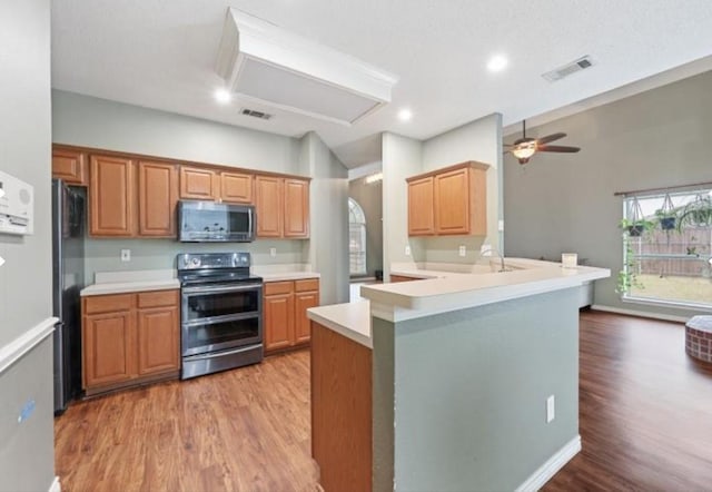 kitchen with hardwood / wood-style flooring, ceiling fan, kitchen peninsula, and stainless steel appliances