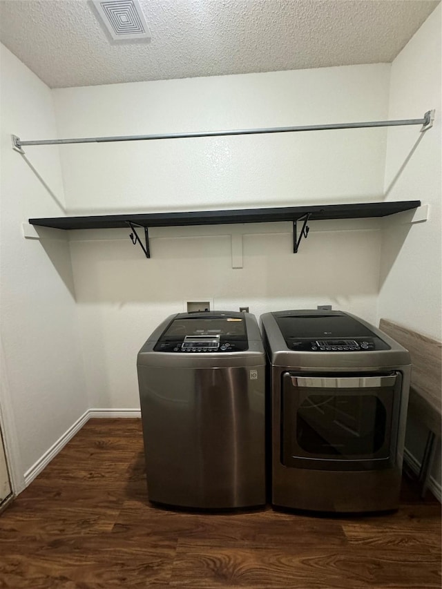 clothes washing area featuring dark hardwood / wood-style floors, washing machine and dryer, and a textured ceiling