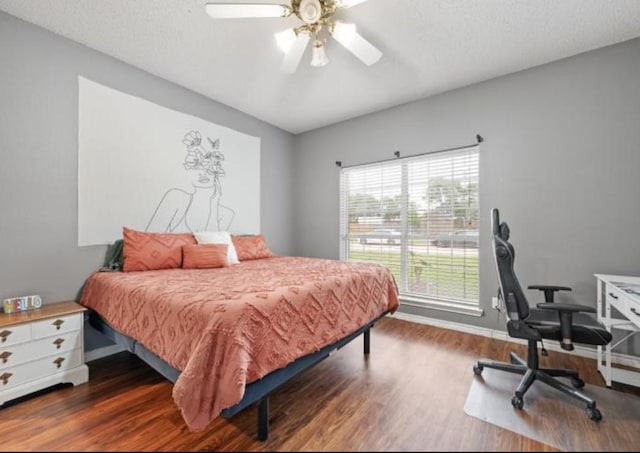 bedroom featuring ceiling fan, dark hardwood / wood-style floors, and a textured ceiling