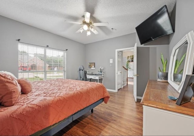 bedroom with ceiling fan, hardwood / wood-style floors, and a textured ceiling