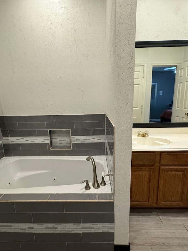 bathroom with vanity and tiled tub