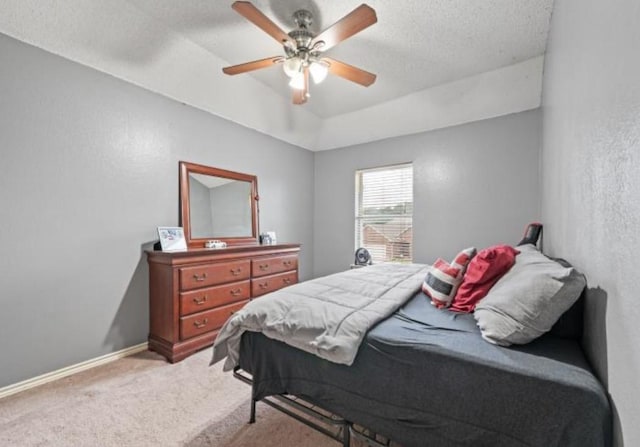 bedroom with carpet flooring, a raised ceiling, ceiling fan, and a textured ceiling