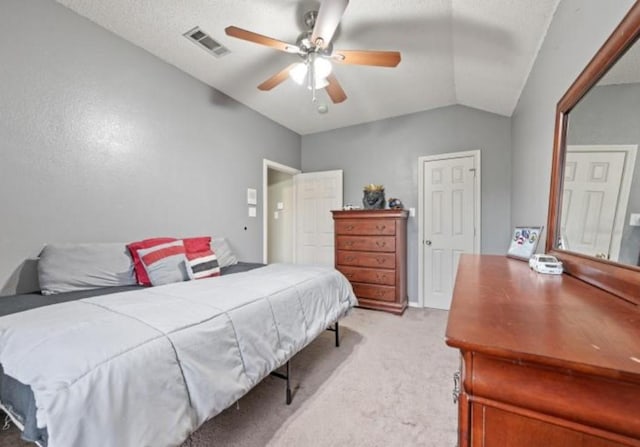 carpeted bedroom with a textured ceiling, ceiling fan, and vaulted ceiling