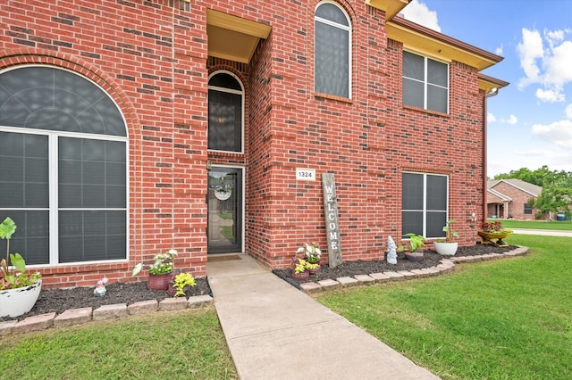 view of exterior entry featuring a lawn