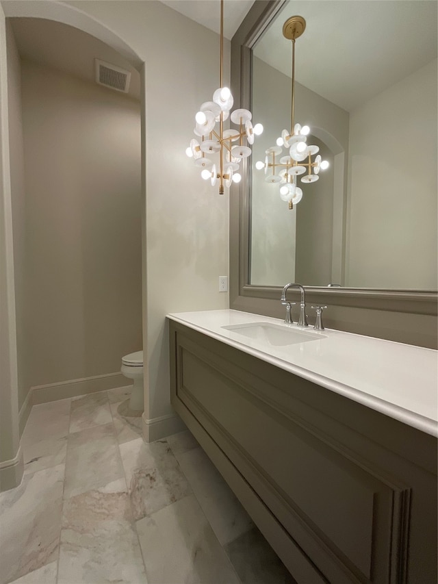 bathroom featuring vanity, toilet, and a chandelier