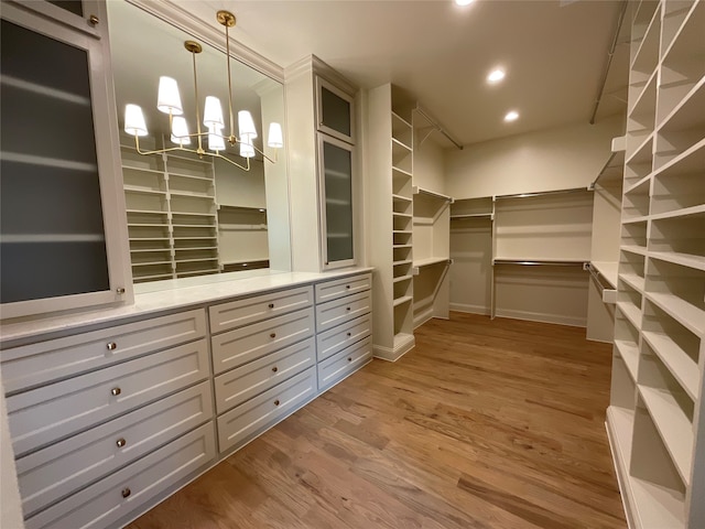 spacious closet with a notable chandelier and light hardwood / wood-style flooring