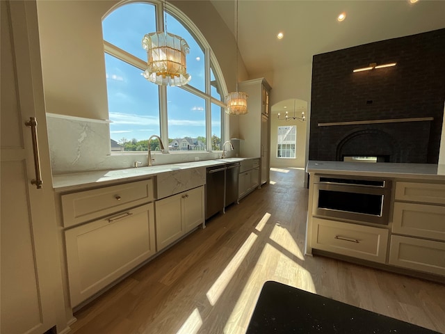 kitchen featuring white cabinets, a fireplace, pendant lighting, stainless steel appliances, and a chandelier