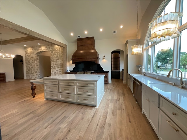 kitchen with pendant lighting, custom exhaust hood, light hardwood / wood-style flooring, white cabinetry, and vaulted ceiling