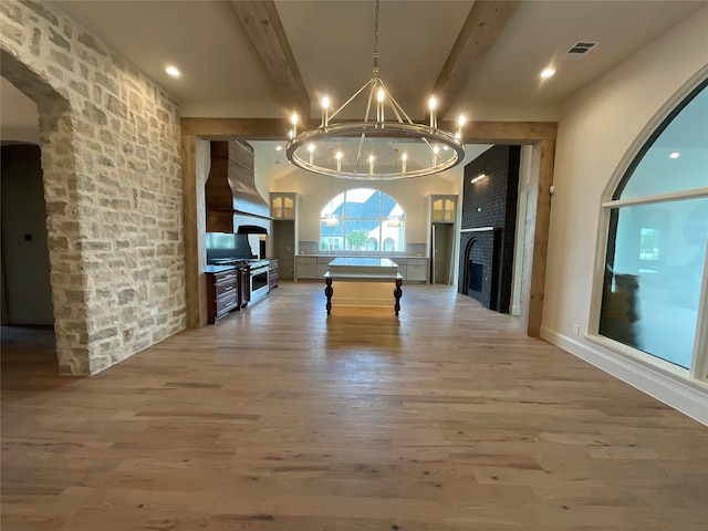 game room with a fireplace, beam ceiling, hardwood / wood-style floors, and a notable chandelier