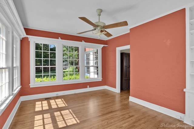 empty room featuring hardwood / wood-style flooring, ceiling fan, crown molding, and built in shelves