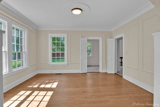 empty room with light wood-type flooring and ornamental molding