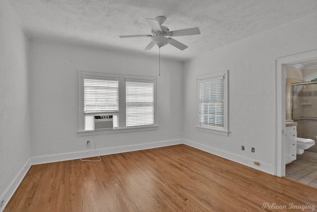 spare room with ceiling fan, light hardwood / wood-style floors, a textured ceiling, and cooling unit