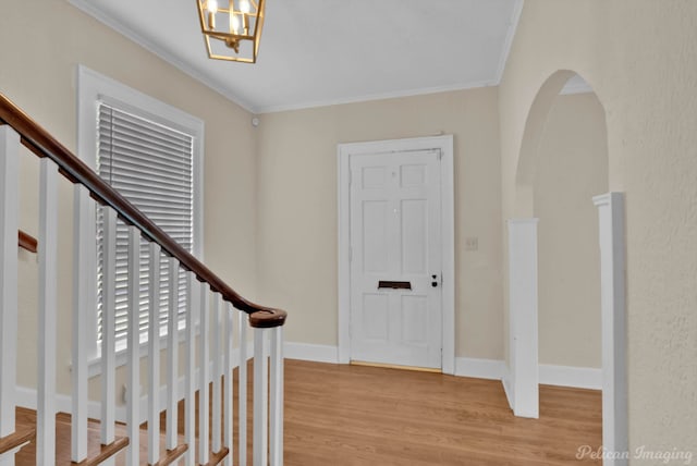 foyer entrance featuring light wood-type flooring, an inviting chandelier, and ornamental molding